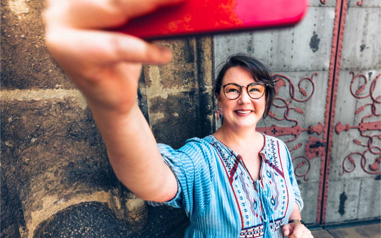 Frau macht mit Handy ein Selfie vor historischer Tür